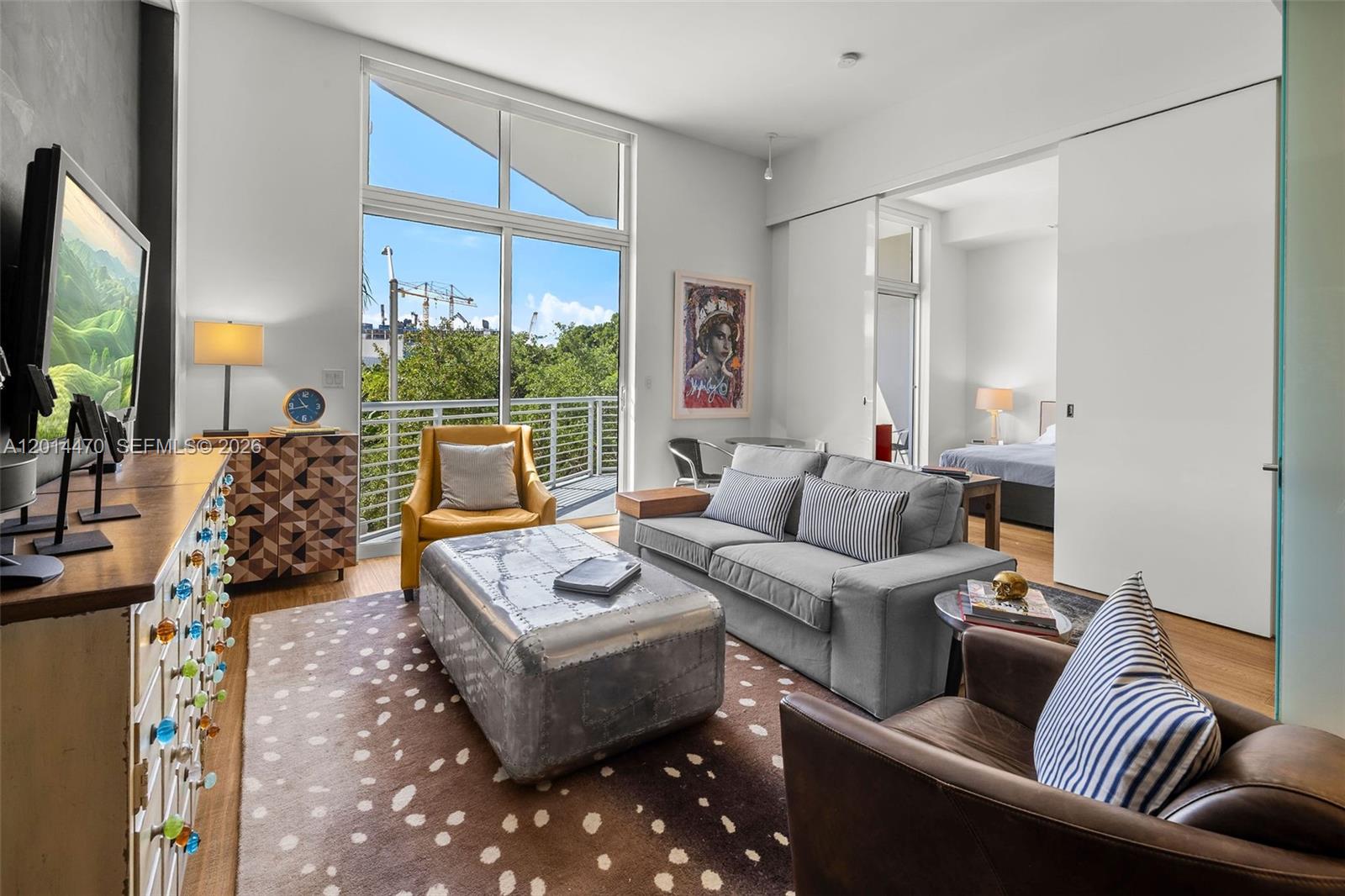 A living room features a grey sofa, metal coffee table, and large windows with balcony access — 2001 Meridian Ave # 404, Miami Beach FL 33139, MIAMI BEACH, FL