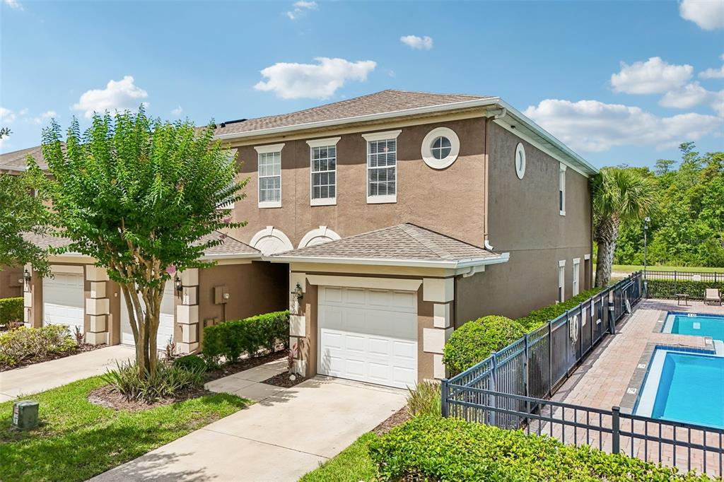 A two-story brown stucco townhouse with a garage and an adjacent swimming pool — 3506 VICTORIA PINES DRIVE UNIT 150, ORLANDO, FL