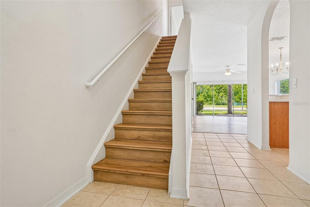 A staircase with wood-look treads and a white handrail sits beside a tiled entryway — 3506 VICTORIA PINES DRIVE UNIT 150, ORLANDO, FL