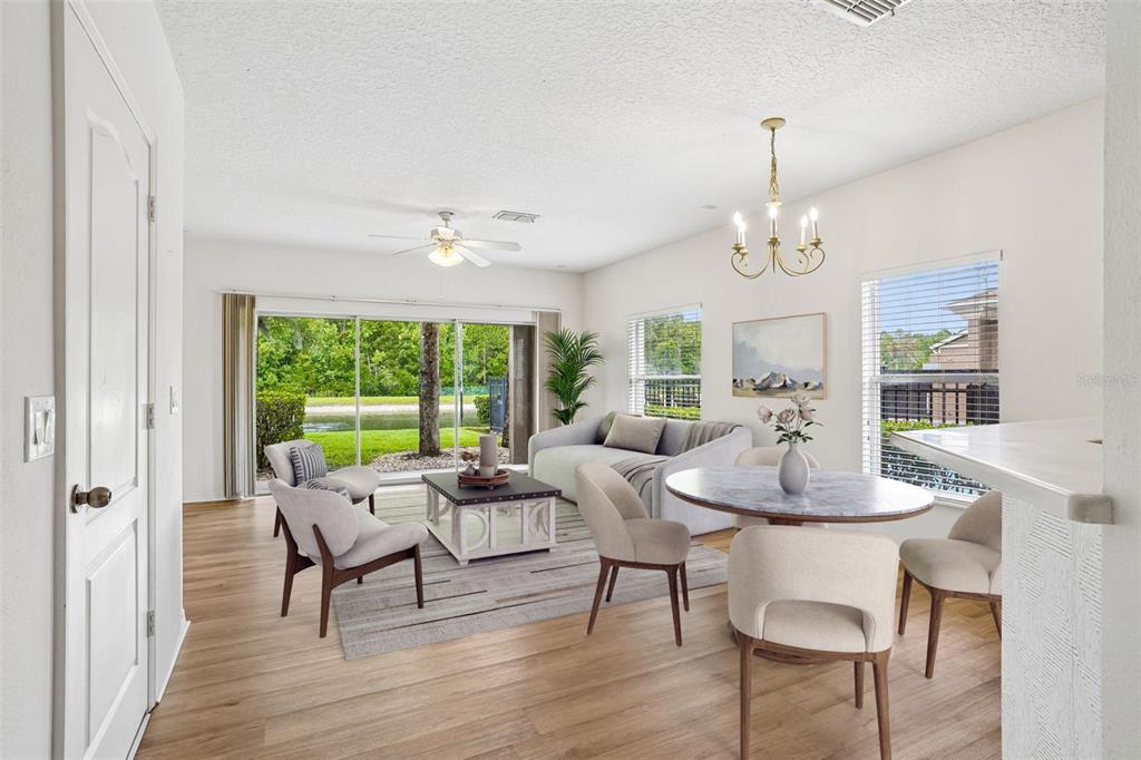 A bright living and dining area features light wood flooring, a sliding glass door, and furniture — 3506 VICTORIA PINES DRIVE UNIT 150, ORLANDO, FL
