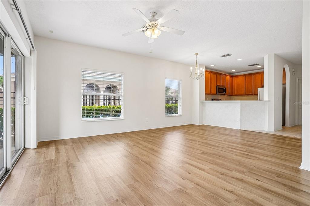An open-concept living room with light wood-look flooring, a ceiling fan, and a kitchen — 3506 VICTORIA PINES DRIVE UNIT 150, ORLANDO, FL