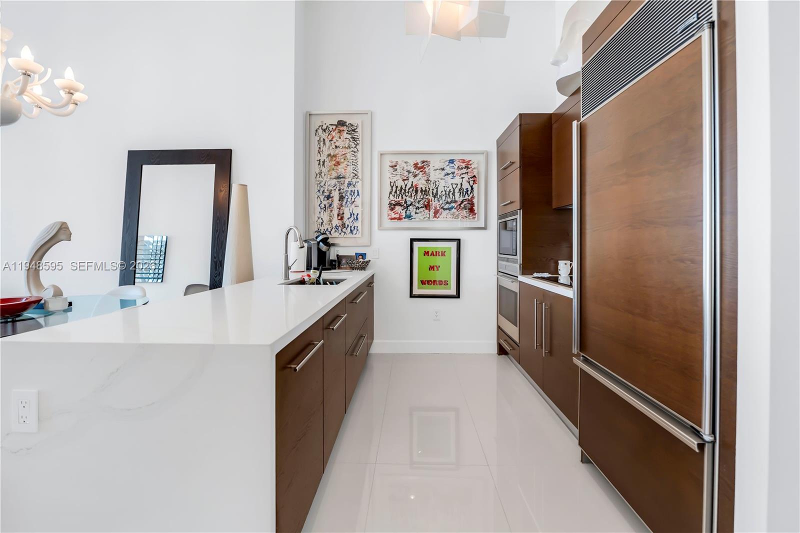 A modern kitchen features wood cabinetry, white countertops, stainless steel appliances, and white tile flooring — 465 Brickell Ave # 4106, Miami FL 33131, MIAMI, FL
