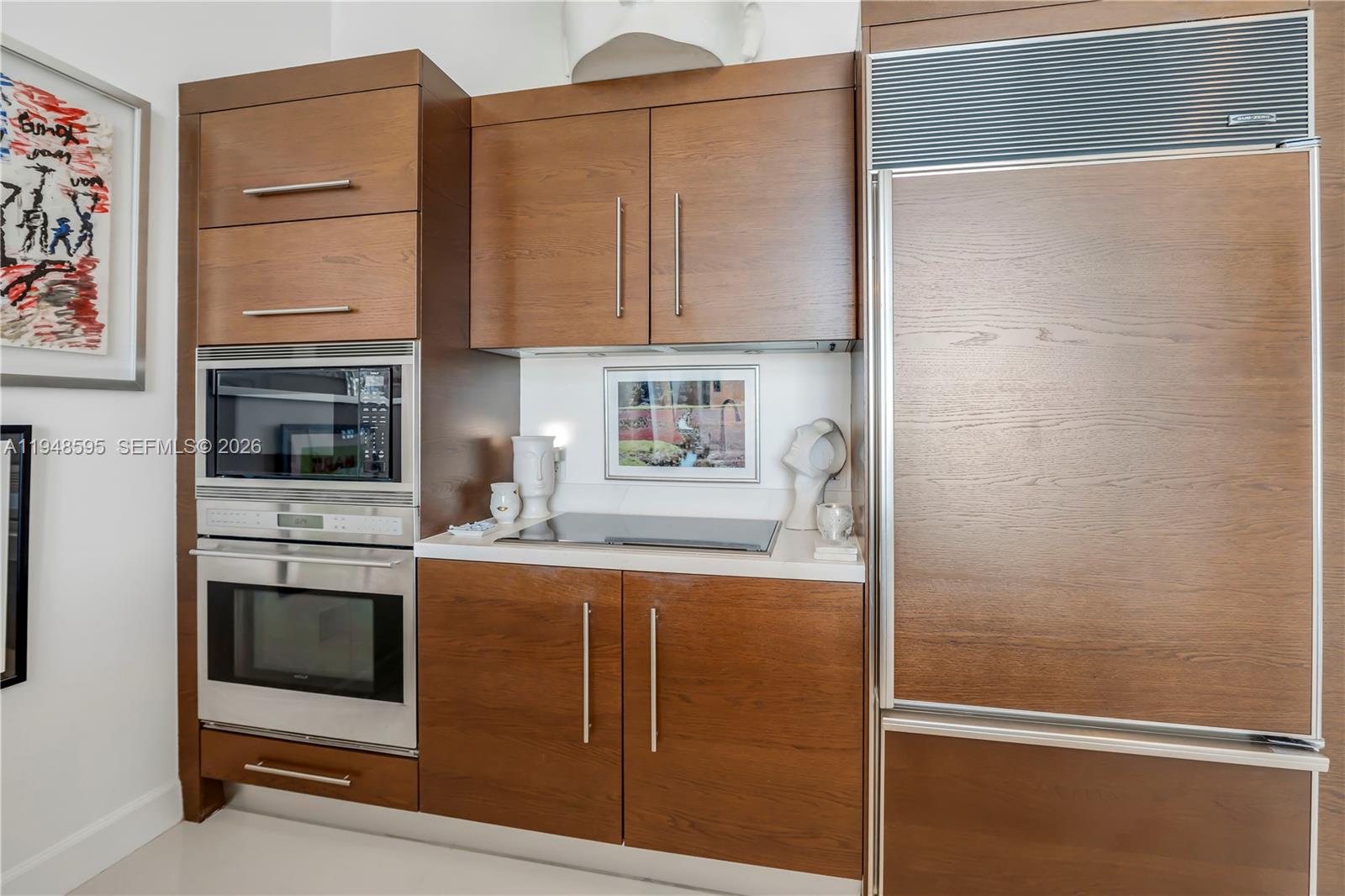 A modern kitchen features wood cabinetry, stainless steel appliances, and a built-in cooktop — 465 Brickell Ave # 4106, Miami FL 33131, MIAMI, FL