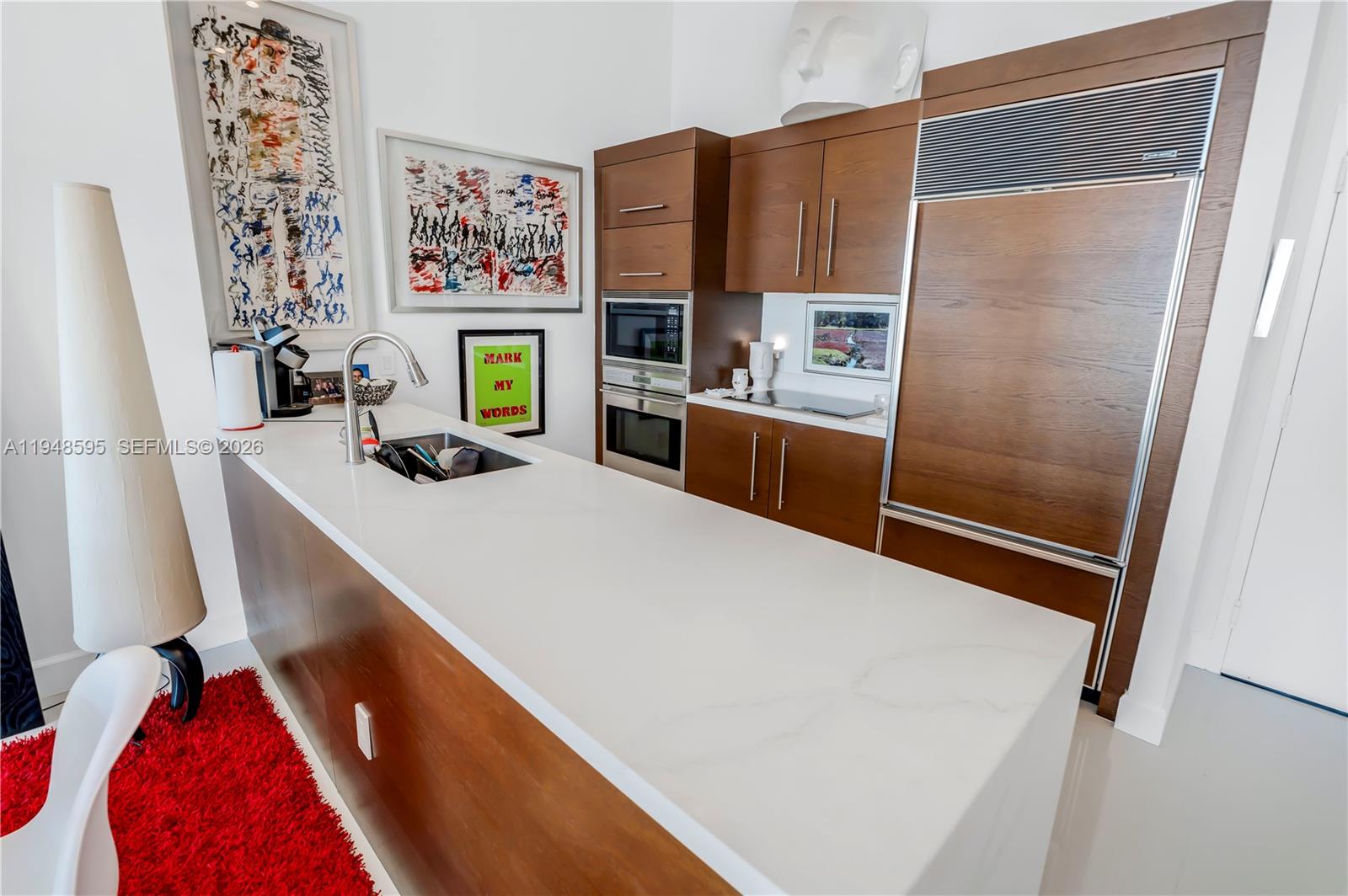 A modern kitchen features a white countertop island, wood cabinetry, and stainless steel appliances — 465 Brickell Ave # 4106, Miami FL 33131, MIAMI, FL