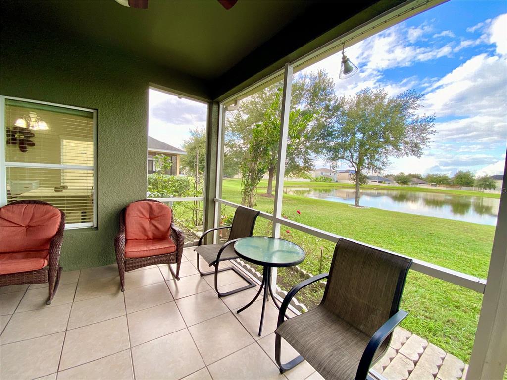 A screened-in patio with tile flooring, outdoor furniture, and a view of a pond — 10812 ANCIENT FUTURES DRIVE, TAMPA, FL
