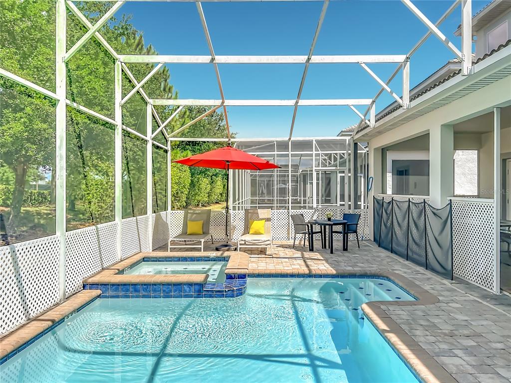 A screened-in patio features a swimming pool with an attached hot tub and outdoor furniture — 1556 MAIDSTONE COURT, DAVENPORT, FL