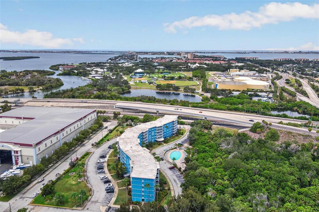 An aerial view shows a curved blue apartment building with a pool near a highway — 3315 58TH AVENUE S UNIT 105, ST PETERSBURG, FL