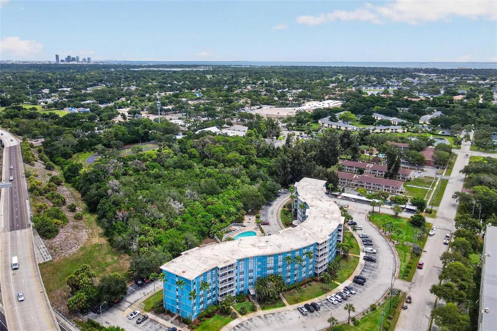 An aerial view shows a curved blue apartment building with a pool and parking lot — 3315 58TH AVENUE S UNIT 105, ST PETERSBURG, FL