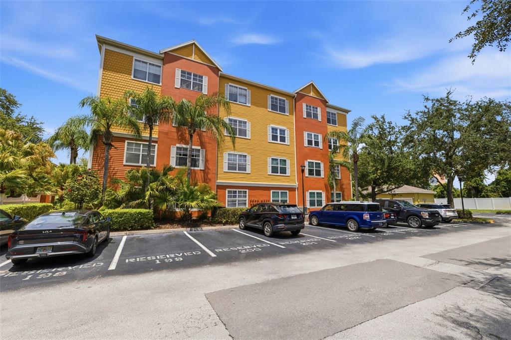 A multi-story apartment building with colorful siding stands behind a row of reserved parking spaces — 4207 S DALE MABRY HIGHWAY UNIT 2305, TAMPA, FL