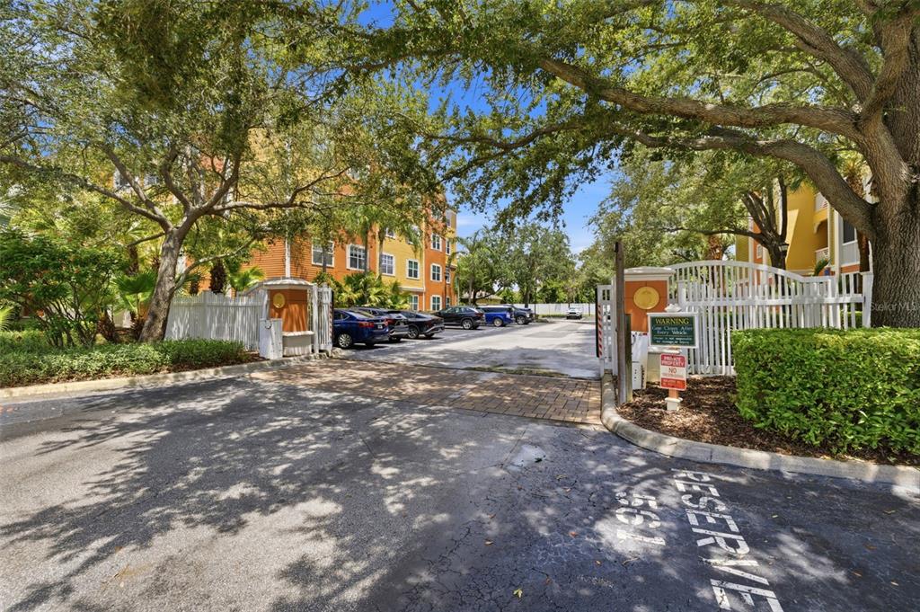 A gated entrance leads to a parking lot between two multi-story apartment buildings with trees — 4207 S DALE MABRY HIGHWAY UNIT 2305, TAMPA, FL