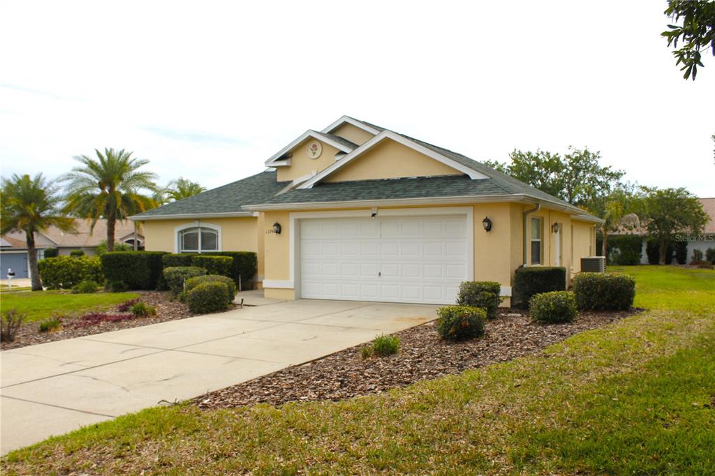 A single-story house with a yellow stucco exterior, a two-car garage, and a shingled roof — 13748 MEADE COURT, HUDSON, FL