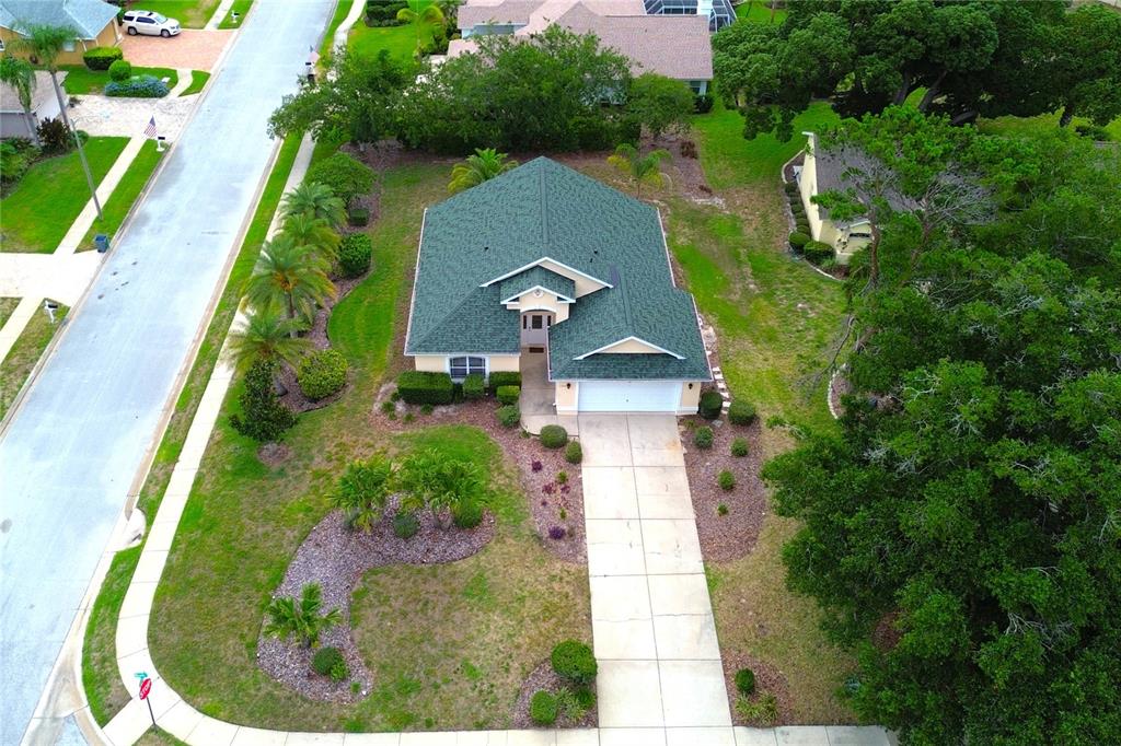 An aerial view shows a single-story house with a green roof, driveway, and landscaped yard — 13748 MEADE COURT, HUDSON, FL