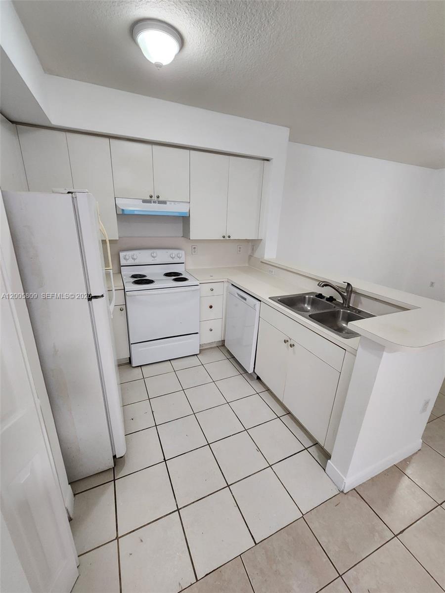 A kitchen features white cabinets, white appliances, a double sink, and tiled flooring — 11060 SW 196th St # 209, Cutler Bay FL 33157, CUTLER BAY, FL