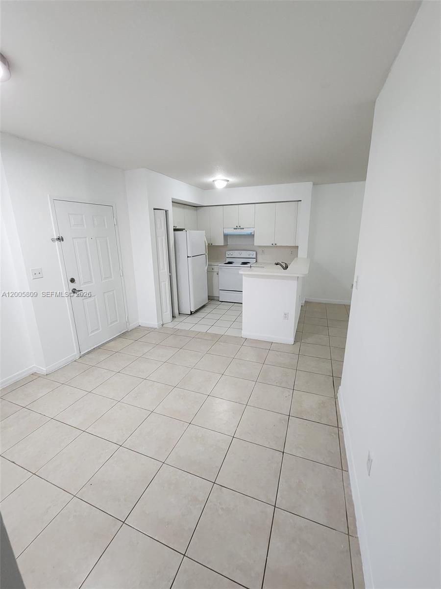 This kitchen features white cabinets, a white refrigerator, a white stove, and tiled flooring — 11060 SW 196th St # 209, Cutler Bay FL 33157, CUTLER BAY, FL