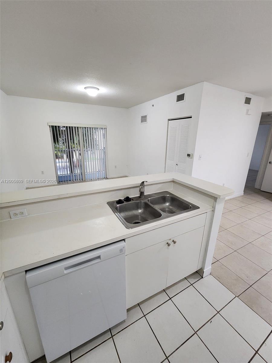 A kitchen features a double-basin sink, white cabinets, a dishwasher, and tiled flooring — 11060 SW 196th St # 209, Cutler Bay FL 33157, CUTLER BAY, FL