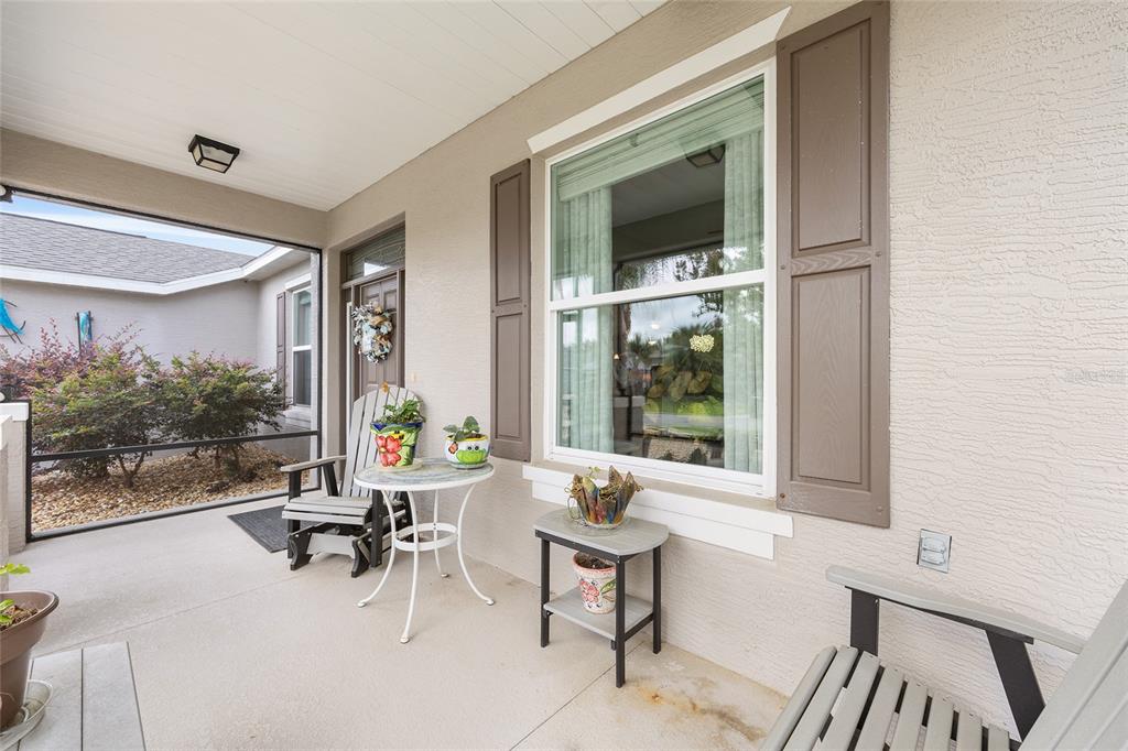 A covered front porch features a seating area, potted plants, and a large window — 4258 JAMES RIVER CIRCLE, LEESBURG, FL