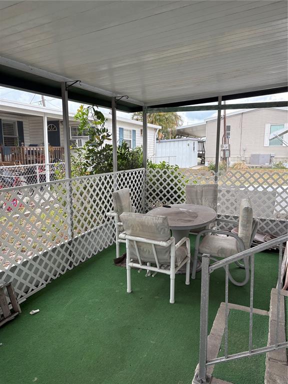 A covered patio with green outdoor carpeting, lattice walls, and a round table with chairs — 6580 SEMINOLE UNIT 102, SEMINOLE, FL
