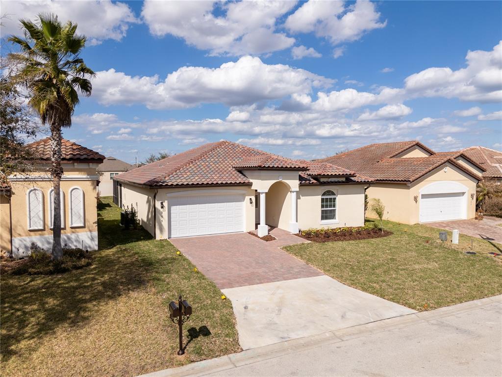 A single-story suburban house with a tile roof, two-car garage, and a paved driveway — 355 VILLA SORRENTO CIRCLE, HAINES CITY, FL