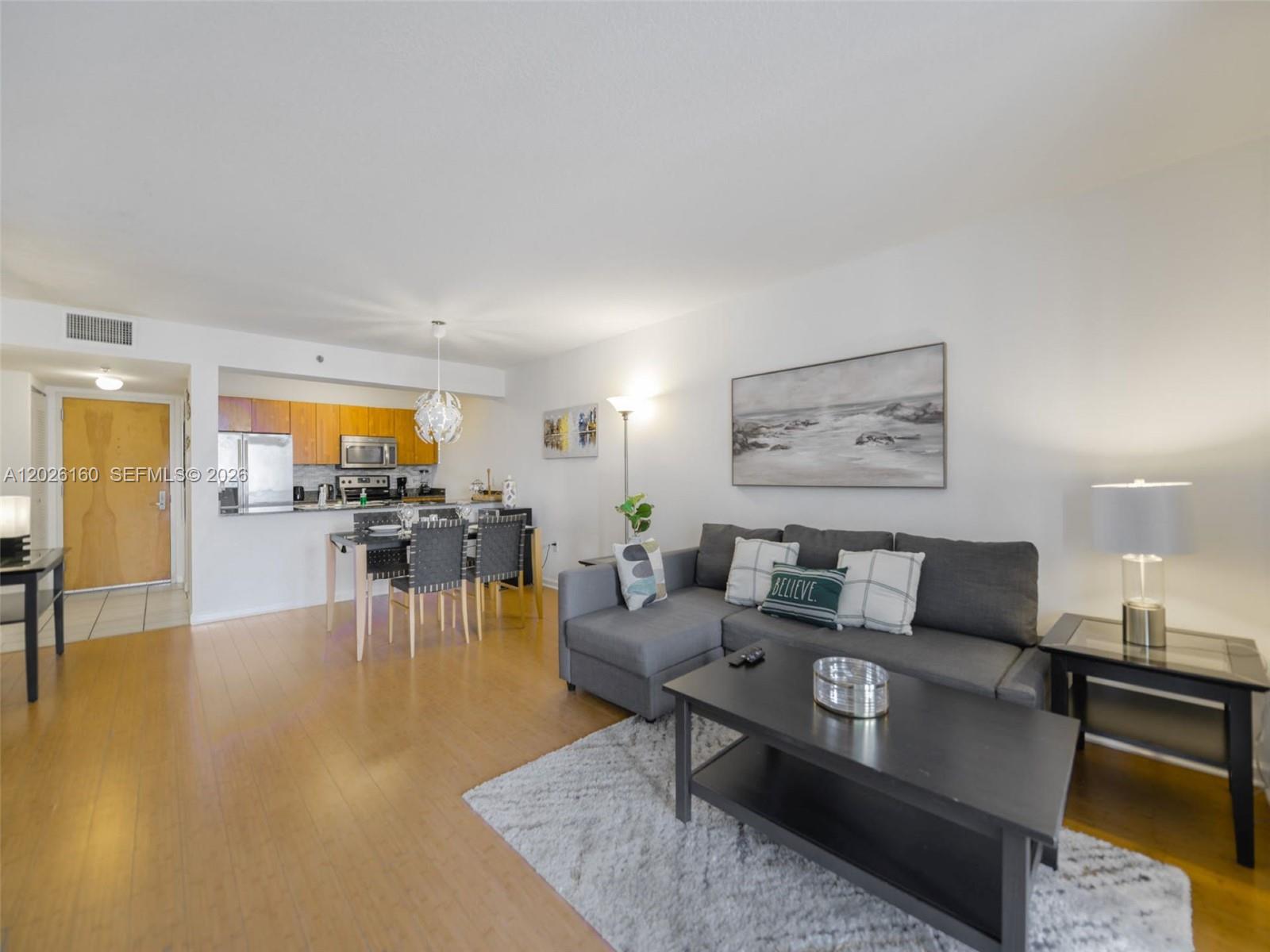 A living room with a gray sectional sofa, coffee table, and an adjacent dining area — 1200 Brickell Bay Dr # 2119, Miami FL 33131, MIAMI, FL
