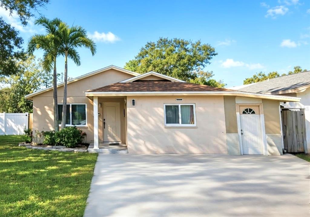 A single-story house with a beige exterior, a concrete driveway, and two palm trees — 7154 63RD STREET N, PINELLAS PARK, FL