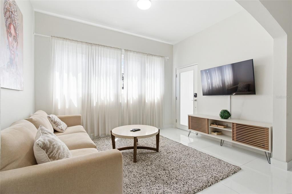 A living room features a beige sofa, a round coffee table, and a wall-mounted television — 56 CALLE F KRUG CONDADO UNIT 1, SAN JUAN, PR