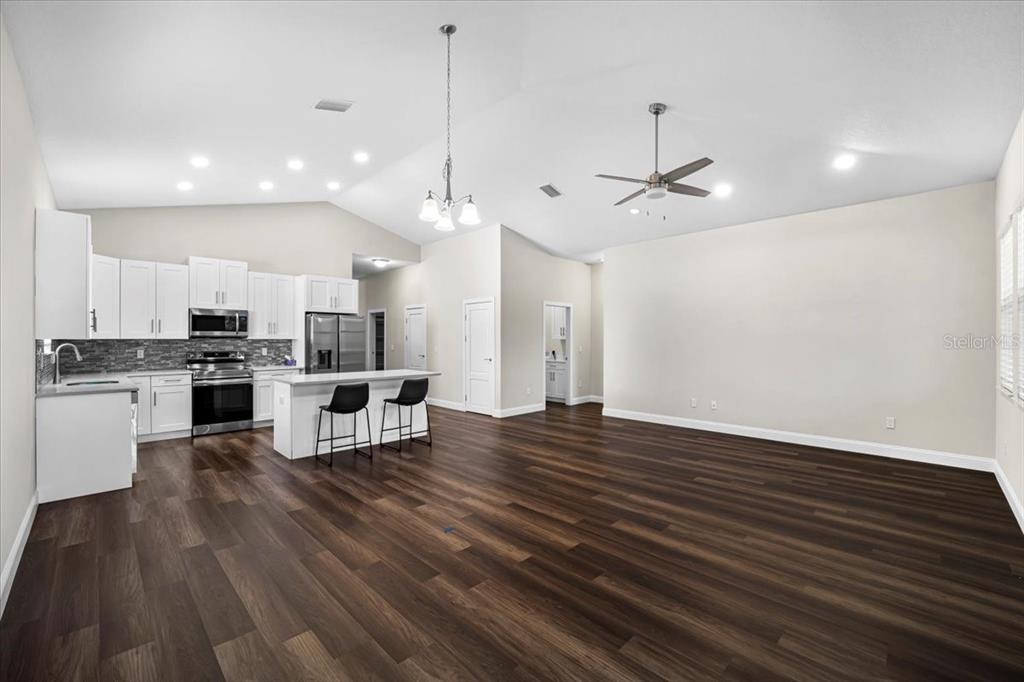 A kitchen with white cabinets and an island opens into a spacious living area — 11 GREEN CIRCLE, PALM COAST, FL