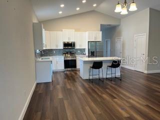 A modern kitchen features white cabinetry, stainless steel appliances, a center island, and wood flooring — 11 GREEN CIRCLE, PALM COAST, FL