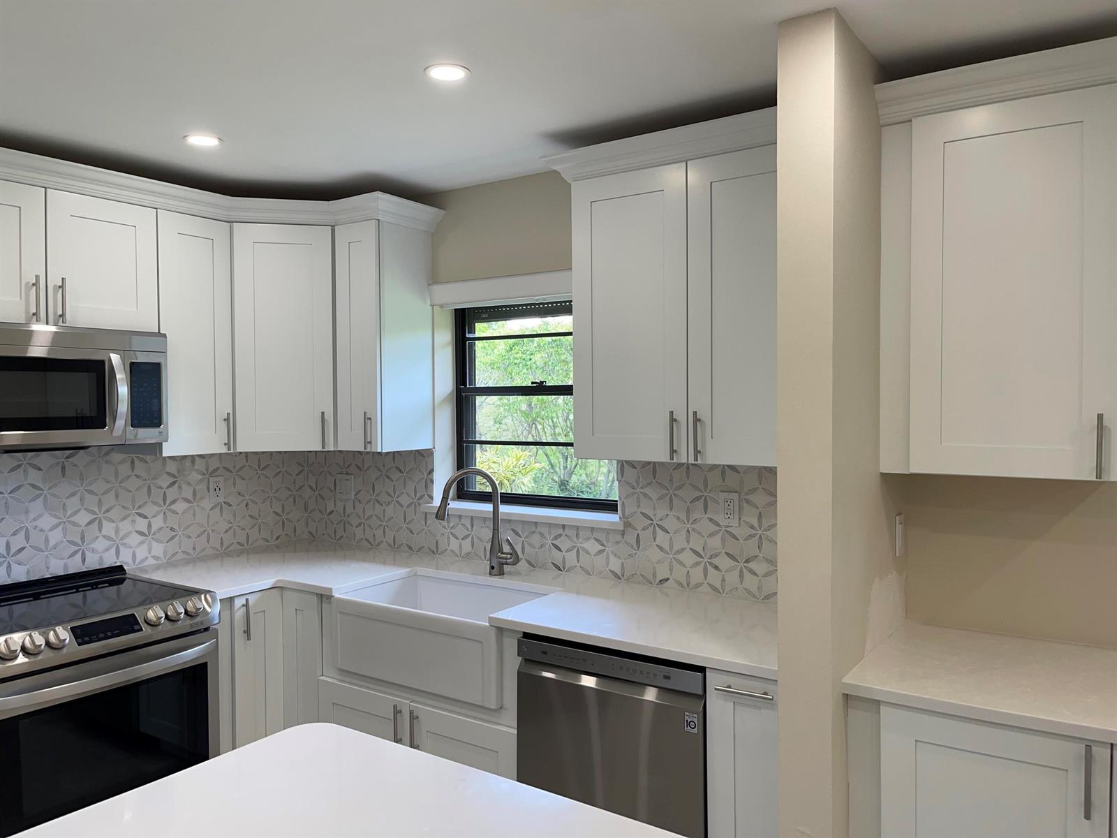 A modern kitchen features white shaker cabinets, stainless steel appliances, a farmhouse sink, and patterned tile — 29 Bethesda Park Circle # G29, Boynton Beach FL 33435, BOYNTON BEACH, FL