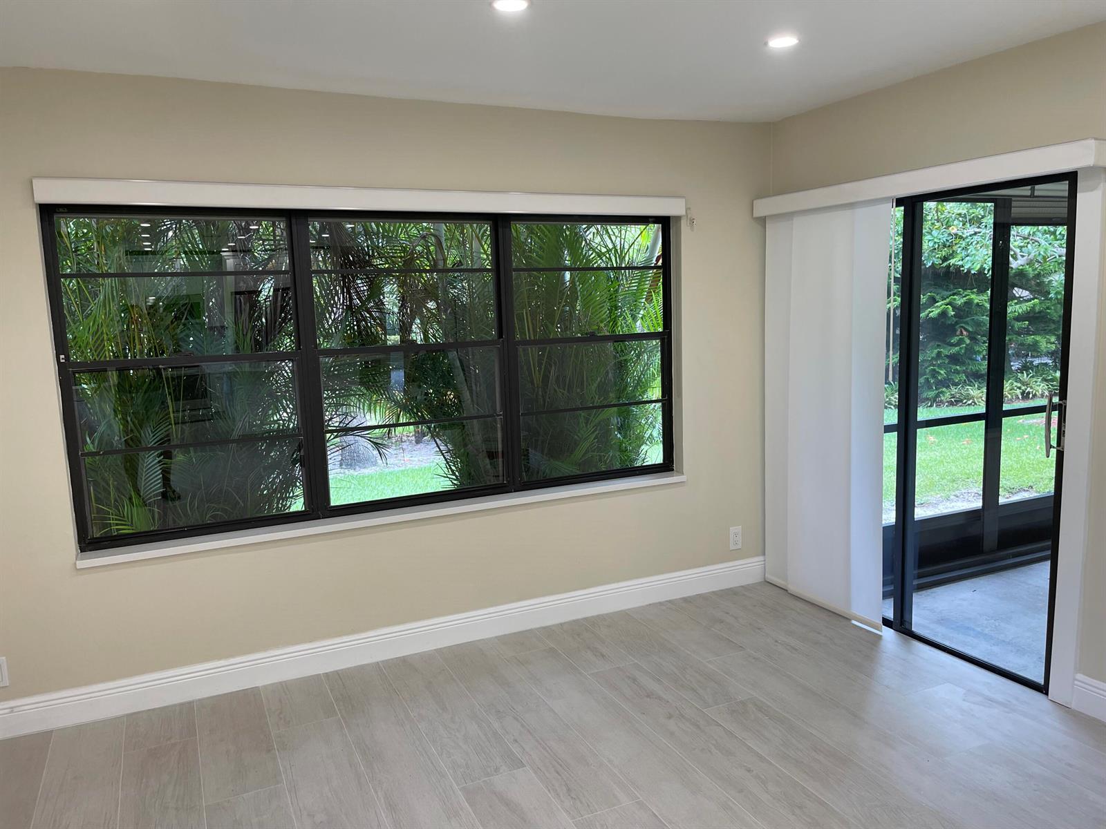 A room with light-colored tile flooring, beige walls, a large window, and a sliding door — 29 Bethesda Park Circle # G29, Boynton Beach FL 33435, BOYNTON BEACH, FL