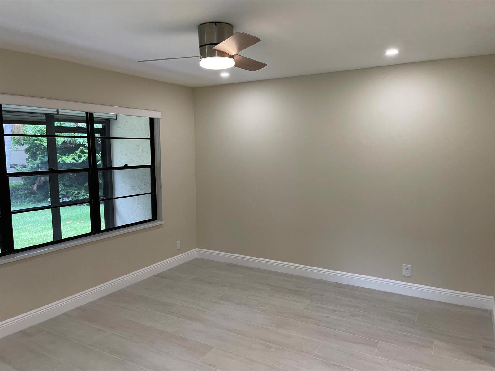 An empty bedroom features light beige walls, wood-look tile flooring, a ceiling fan, and windows — 29 Bethesda Park Circle # G29, Boynton Beach FL 33435, BOYNTON BEACH, FL