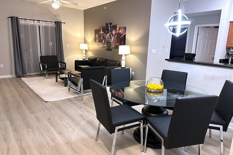 An open-concept living and dining area features modern furniture, light wood flooring, and neutral walls — 8112 POINCIANA BOULEVARD UNIT 1502, ORLANDO, FL