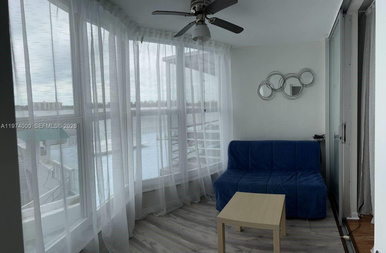 A sunroom features a blue sofa, a small table, and large windows overlooking water — 1150 NE 191st St # 34, Miami FL 33179, MIAMI, FL