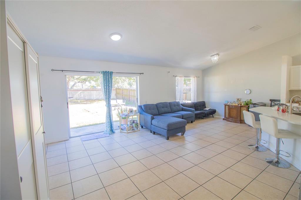 A living room with tile flooring, a blue sectional sofa, and a sliding glass door — 10606 WALKER VISTA DRIVE, RIVERVIEW, FL