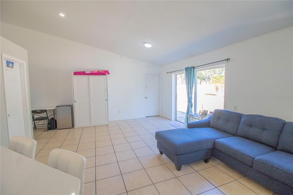 A living room with tile flooring, a blue sectional sofa, and a sliding glass door — 10606 WALKER VISTA DRIVE, RIVERVIEW, FL