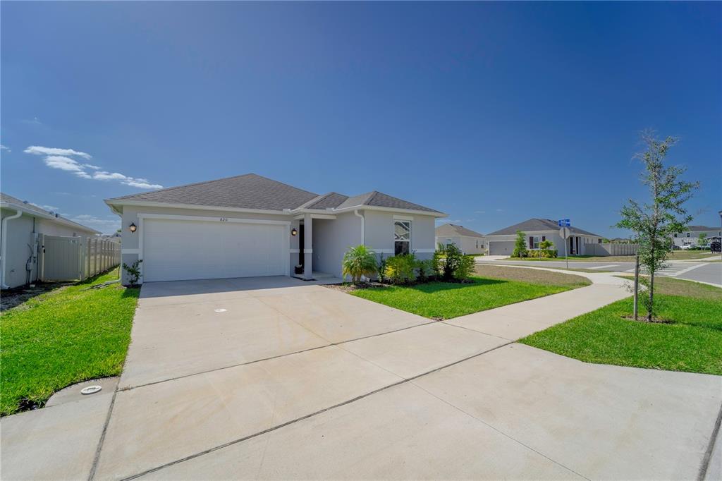 A single-story house with a two-car garage, concrete driveway, and a small front lawn — 820 OVERPOOL AVENUE, DAVENPORT, FL