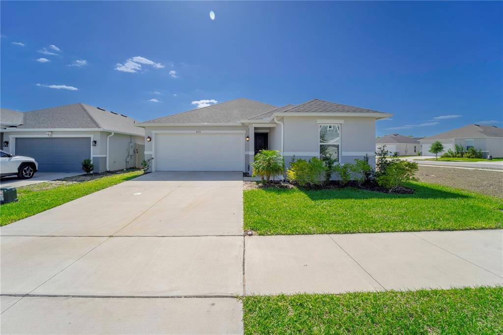 A single-story suburban house with a two-car garage, concrete driveway, and a front lawn — 820 OVERPOOL AVENUE, DAVENPORT, FL