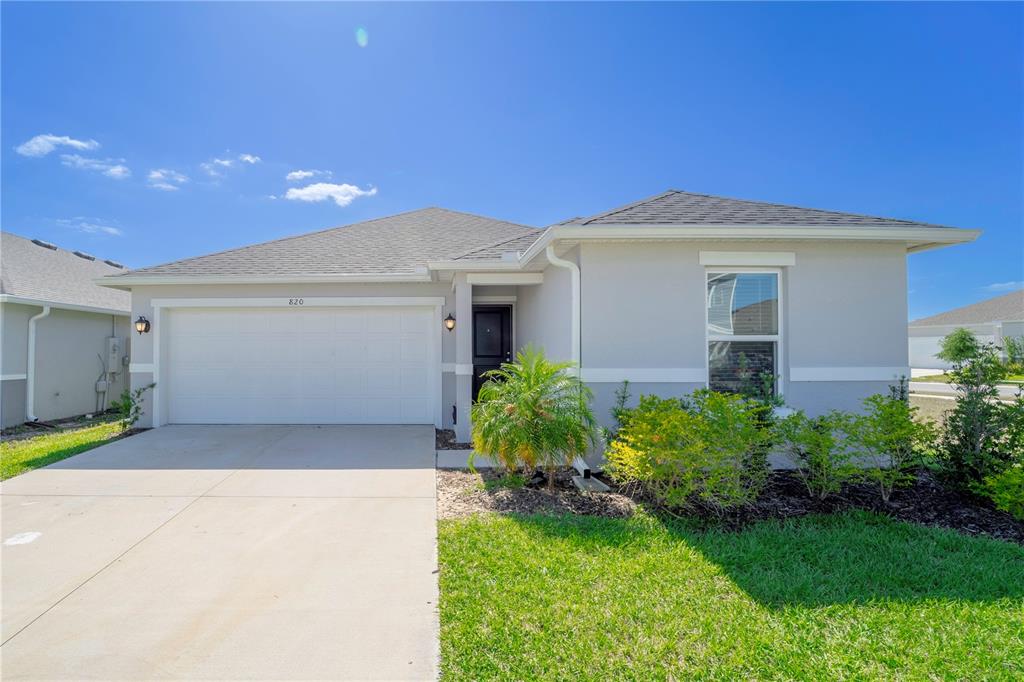 A single-story suburban house with a two-car garage, gray stucco exterior, and front lawn — 820 OVERPOOL AVENUE, DAVENPORT, FL