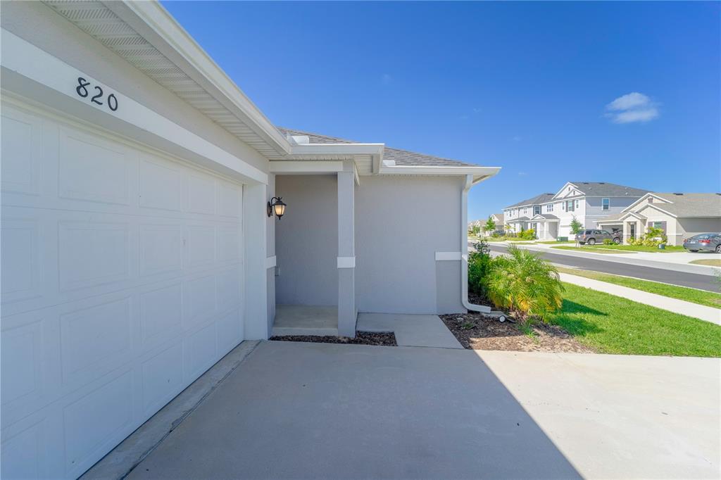 A view of a house exterior featuring a white garage door and a covered entryway — 820 OVERPOOL AVENUE, DAVENPORT, FL