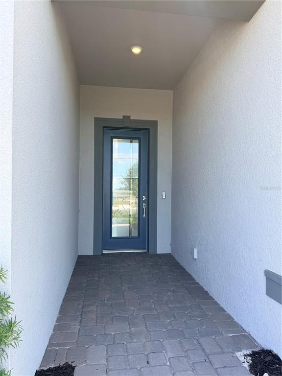 A covered entryway features a blue front door with glass panels and stone pavers — 4821 LONG POINT RUN, LAKEWOOD RANCH, FL