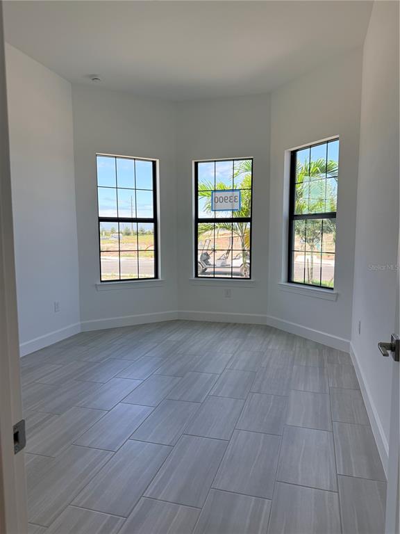 A room with light gray tile flooring and three large windows overlooking a construction site — 4821 LONG POINT RUN, LAKEWOOD RANCH, FL