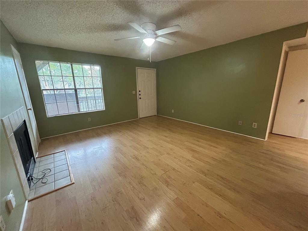 A living room features a fireplace, light wood flooring, a ceiling fan, and neutral furniture — 380 LAKEPOINTE DRIVE UNIT 202, ALTAMONTE SPRINGS, FL