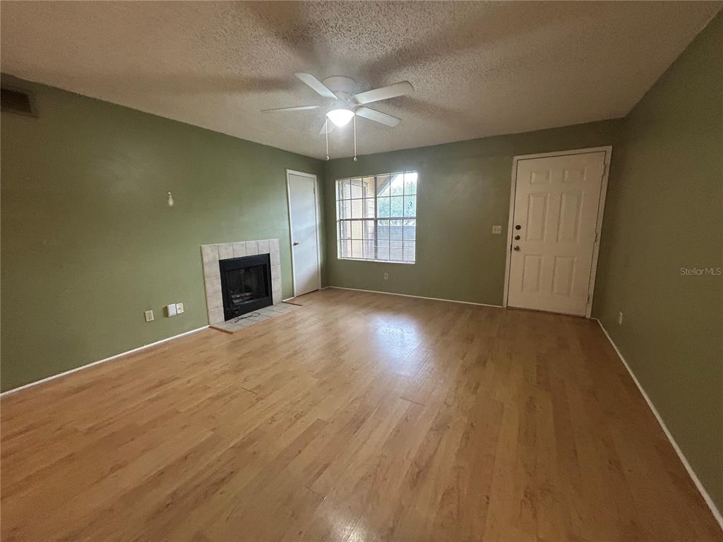 A living room with green walls, wood-look flooring, a fireplace, and a ceiling fan — 380 LAKEPOINTE DRIVE UNIT 202, ALTAMONTE SPRINGS, FL