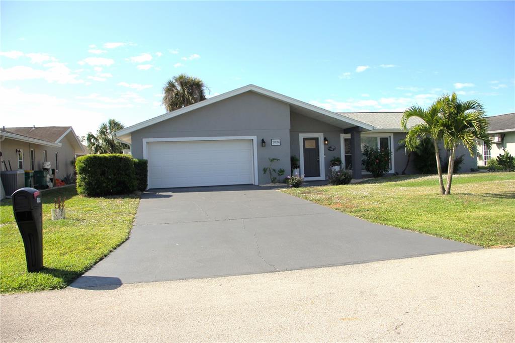 A gray single-story house with a two-car garage, a paved driveway, and a palm tree — 2824 SHANNON DRIVE, PUNTA GORDA, FL