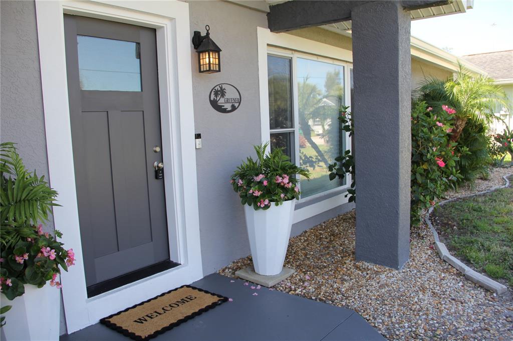 A gray front door with a white frame sits beside a white planter and window — 2824 SHANNON DRIVE, PUNTA GORDA, FL