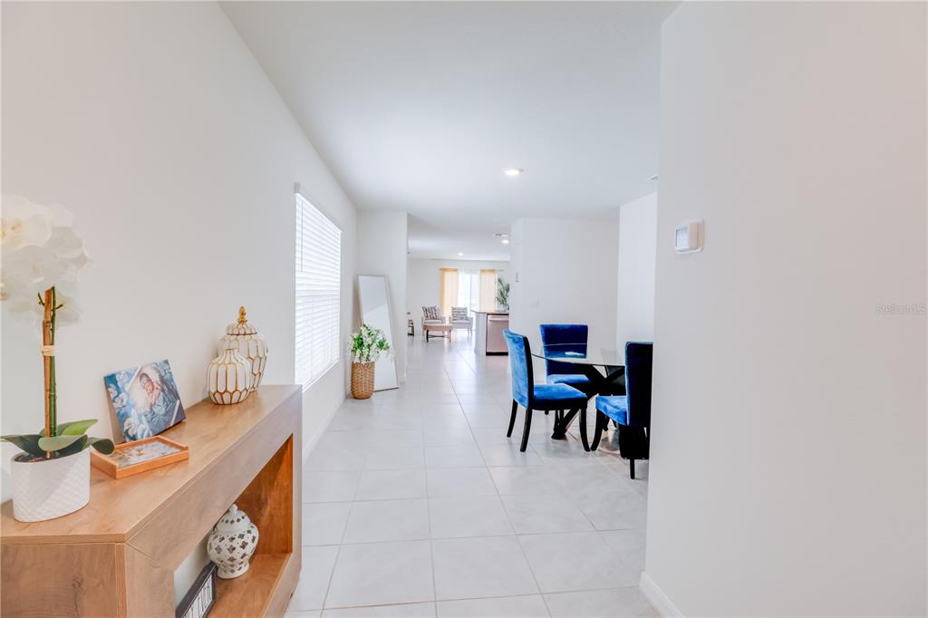 A view from a hallway looking into a dining area and living room with tile floors — 8695 SW 46TH AVENUE, OCALA, FL