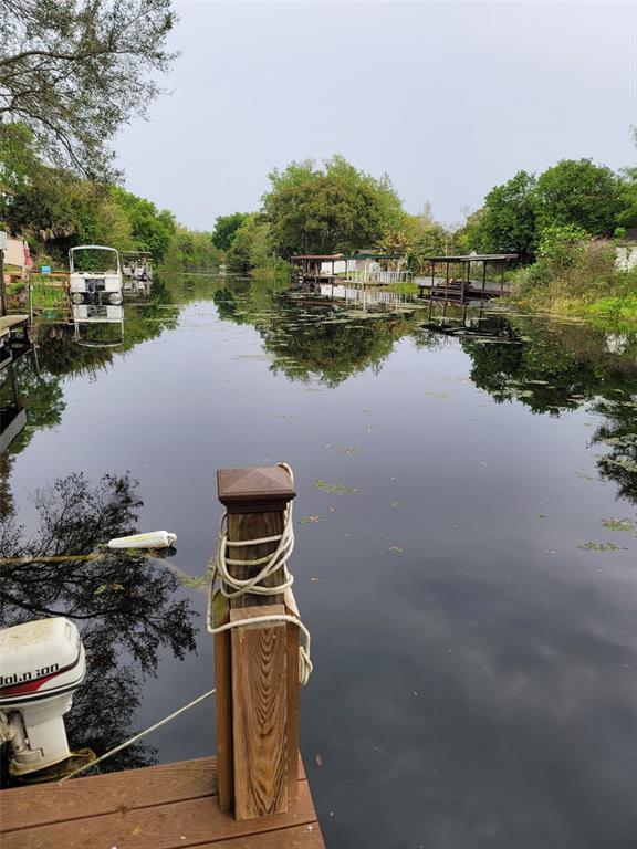 A wooden dock overlooks a calm canal lined with trees, boat slips, and docked boats — 27728 LISA DRIVE, TAVARES, FL
