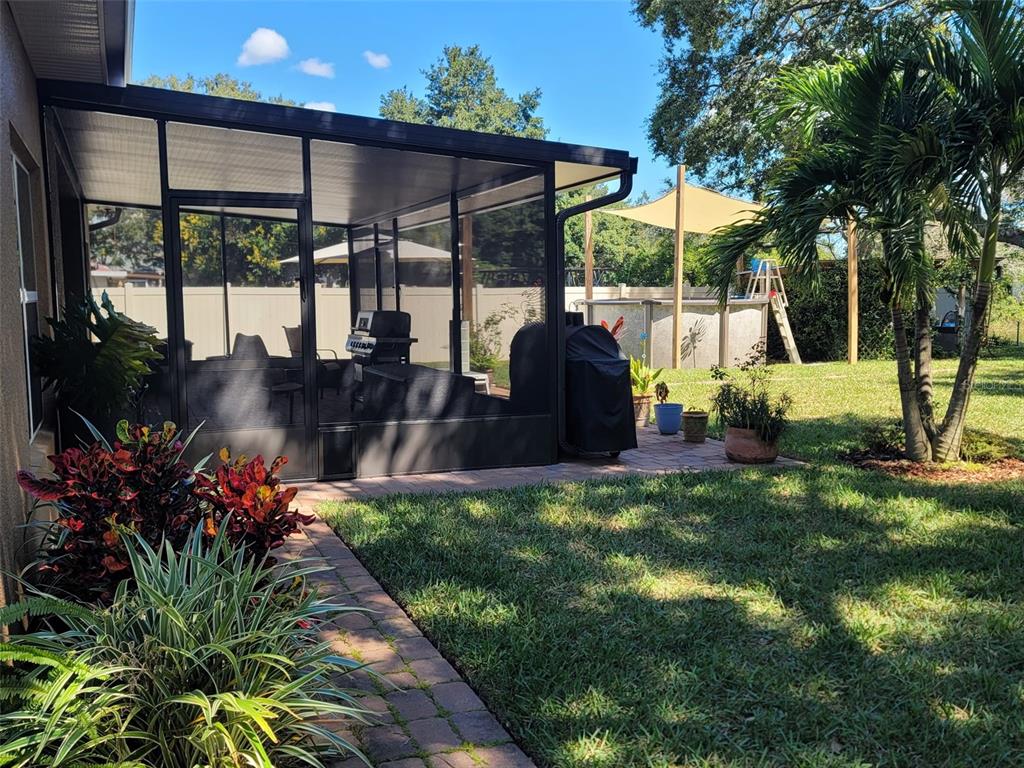 A screened-in patio overlooks a backyard with a pool, a palm tree, and landscaping — 27728 LISA DRIVE, TAVARES, FL