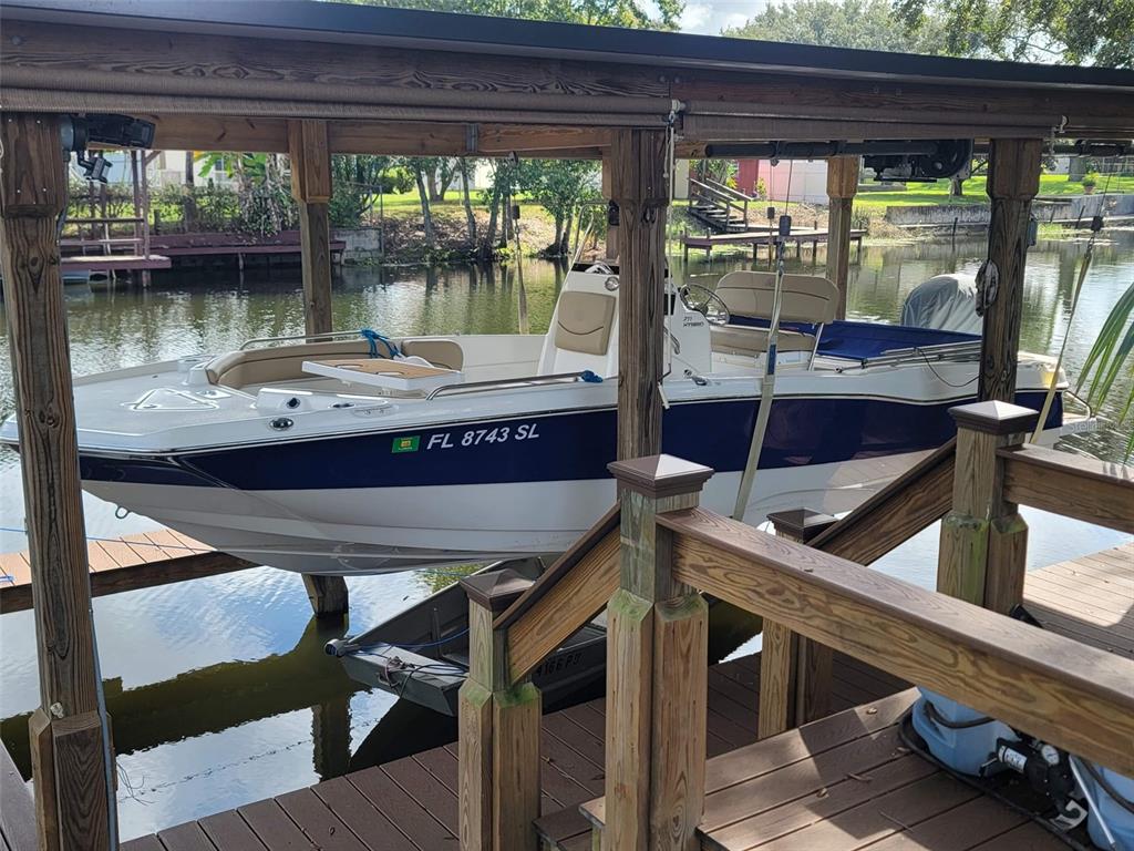 A white and blue motorboat is suspended on a boat lift at a wooden dock — 27728 LISA DRIVE, TAVARES, FL