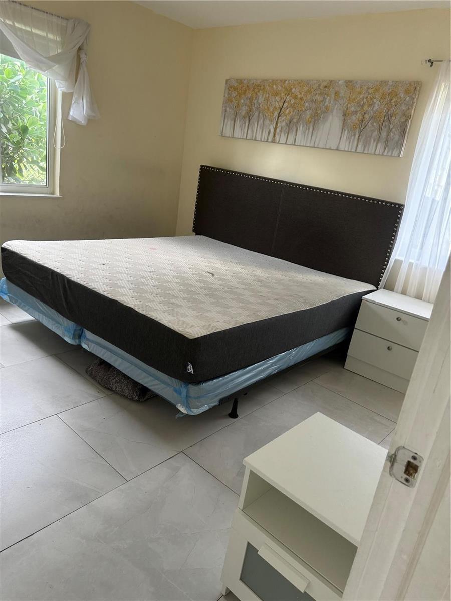 A bedroom features a large bed with a dark headboard and white tile flooring — 2201 Greene Street # 1, Hollywood FL 33020, HOLLYWOOD, FL