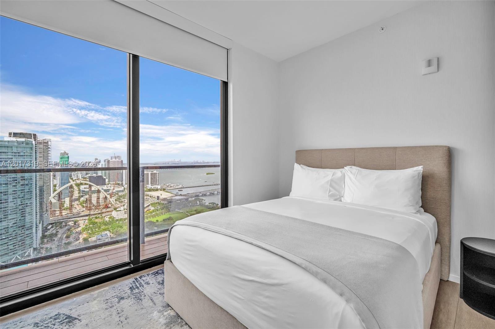 A bedroom features a bed with a tan headboard next to a floor-to-ceiling window — 398 NE 5th St # 4701, Miami FL 33132, MIAMI, FL